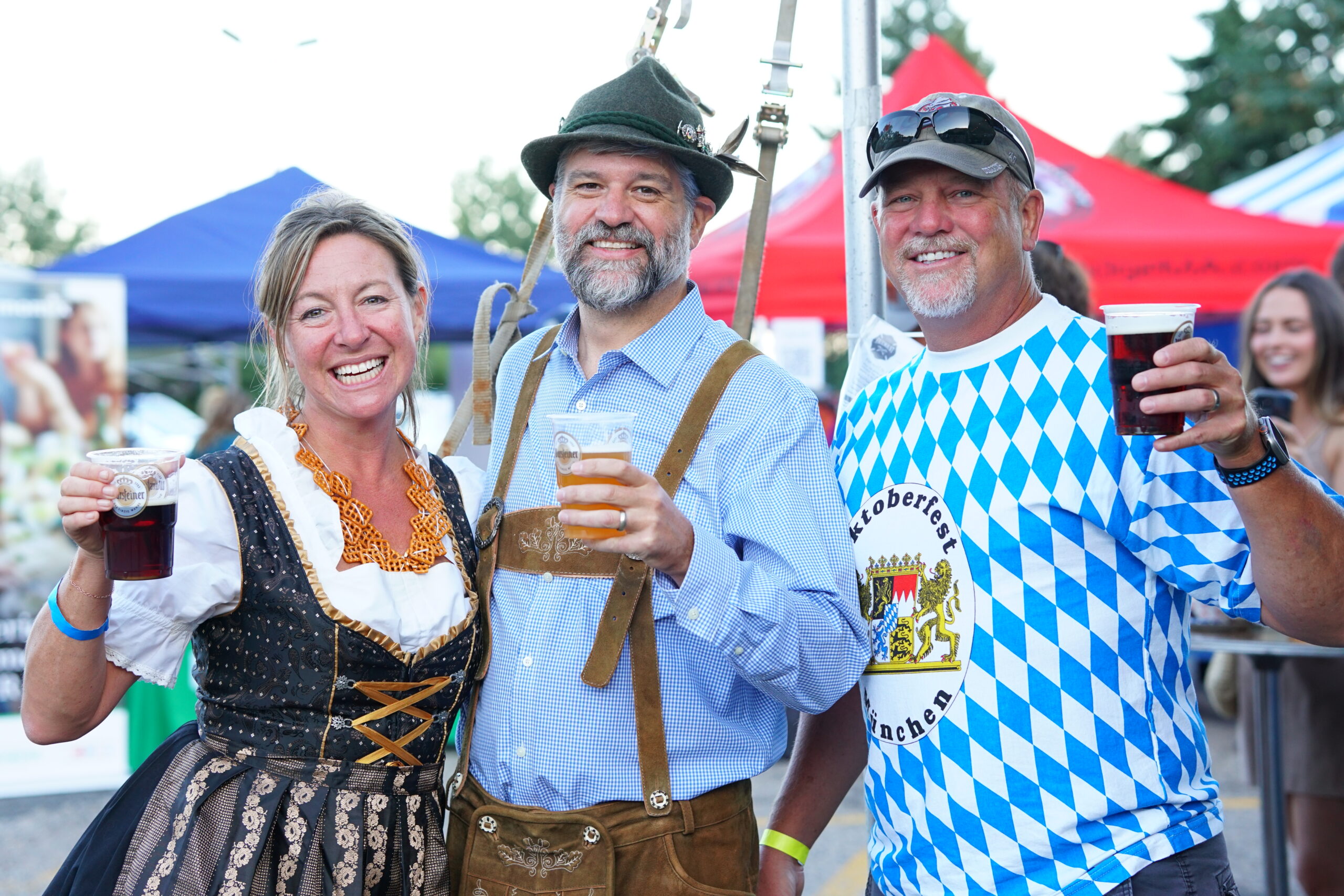 Guests in traditional German attire raising drinks at Denver Kickers Oktoberfest
