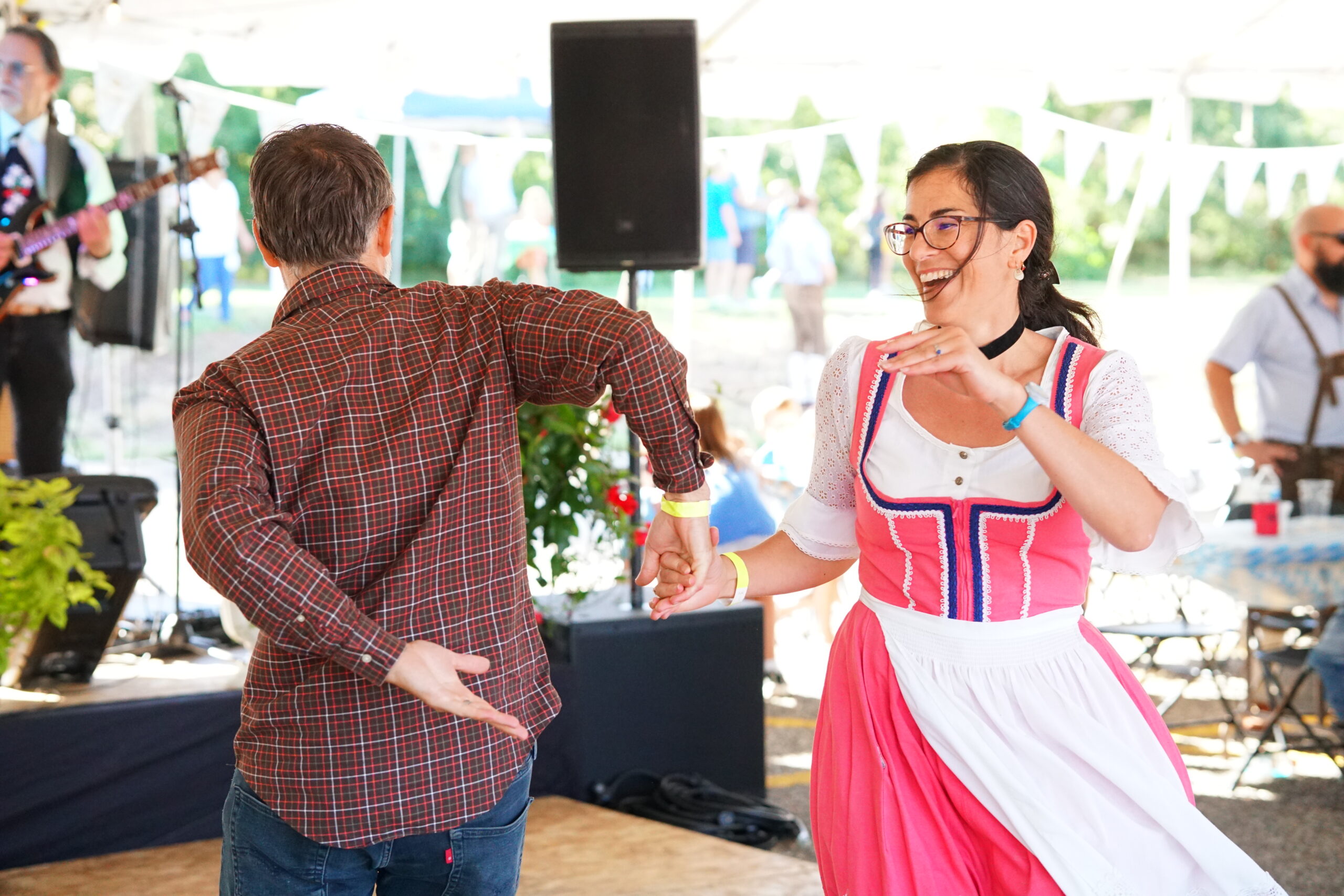 A smiling guest in a dirndl dances with a partner at Oktoberfest