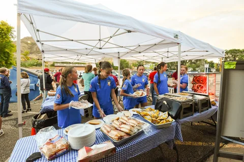 Volunteers serving food beneath an outdoor canopy