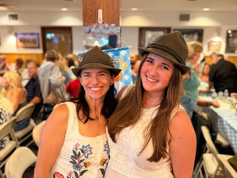 Two friends in Alpine hats smiling at Oktoberfest